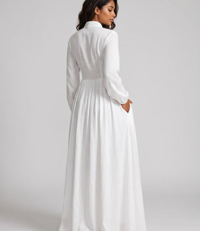 Woman wearing a long white dress against a plain background