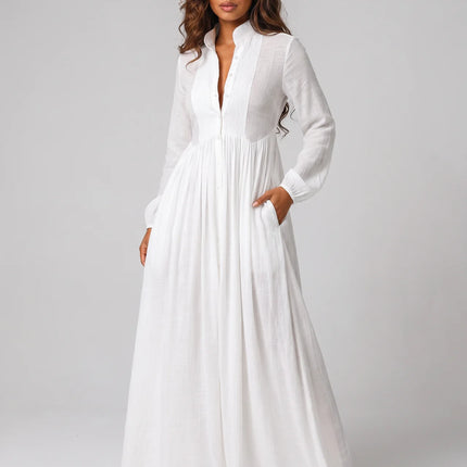 Woman wearing a long white dress against a plain background