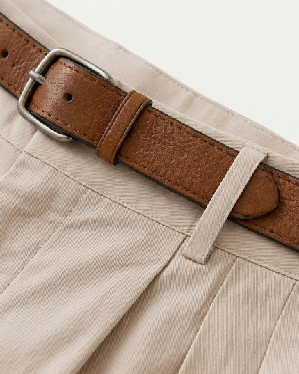 Close-up of brown leather belt with silver buckle on cream chino shorts waistband