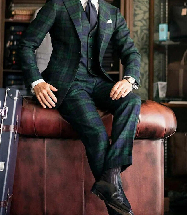 Full length seated view of green and blue tartan formal three piece suit