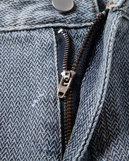 Close-up of metal zipper on textured blue denim shorts with contrast stitching