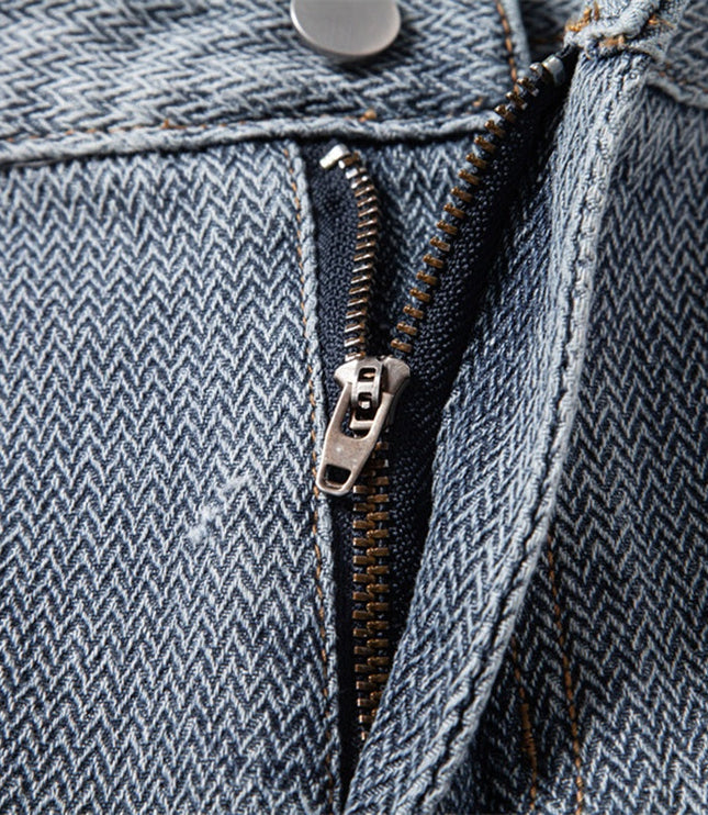 Close-up of metal zipper on textured blue denim shorts with contrast stitching