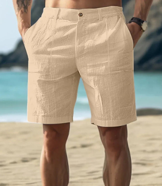 Beige men's linen shorts with flat front and knee length cut in beach setting