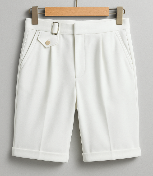 Cream pleated shorts with buckle adjusters and rolled cuffs shown on wooden hanger