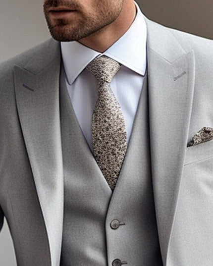 Close-up of light grey suit jacket with grey waistcoat and patterned necktie detail