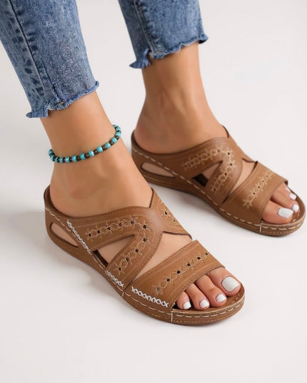 Tan embroidered sandals with multiple straps and decorative stitching on foot