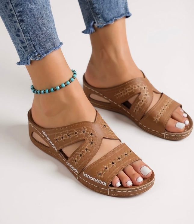 Tan embroidered sandals with multiple straps and decorative stitching on foot