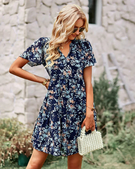 Women's navy blue floral print mini sundress with a v-neck, short flutter sleeves, and a tiered skirt.