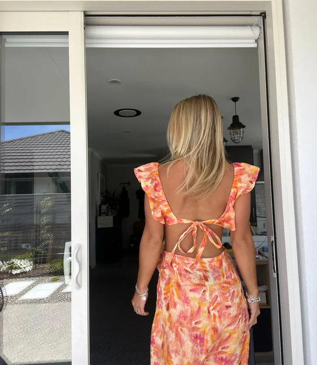 Back view of a women's floral ruffle tie-back maxi sundress, showcasing the open back with a tied bow detail.