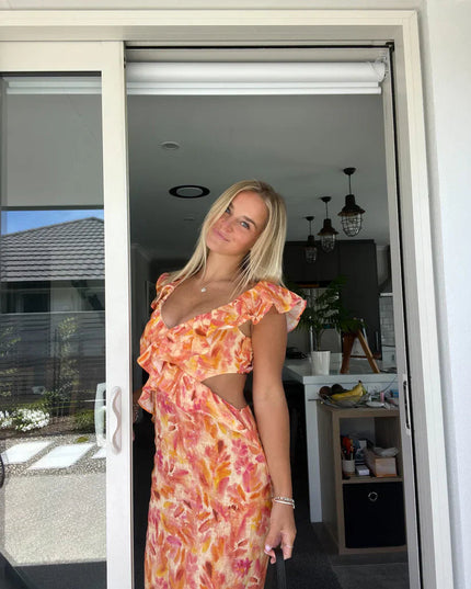 Women's orange and pink floral maxi sundress with ruffle trim and side cutouts, featuring a deep V-neckline.