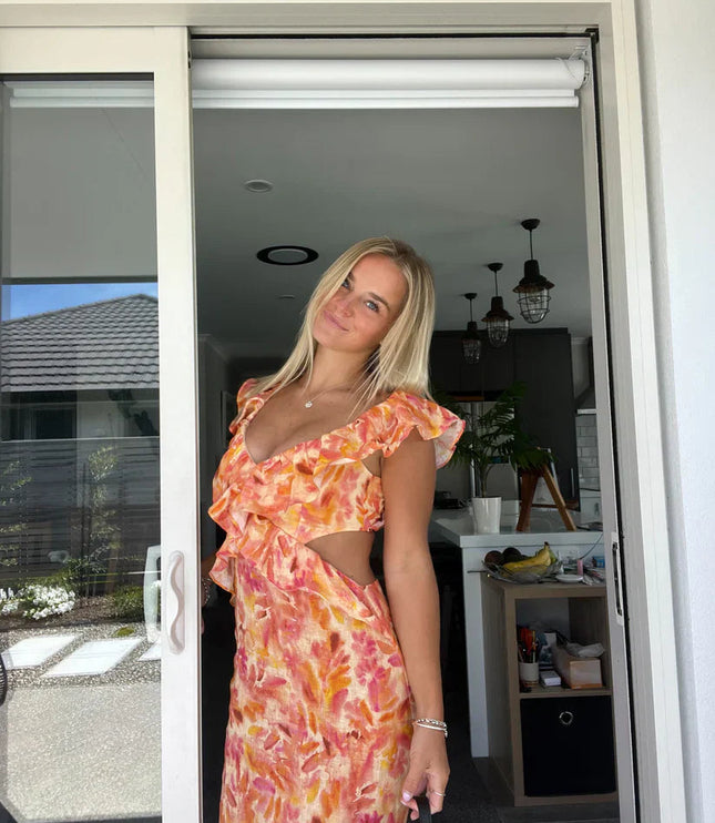 Women's orange and pink floral maxi sundress with ruffle trim and side cutouts, featuring a deep V-neckline.