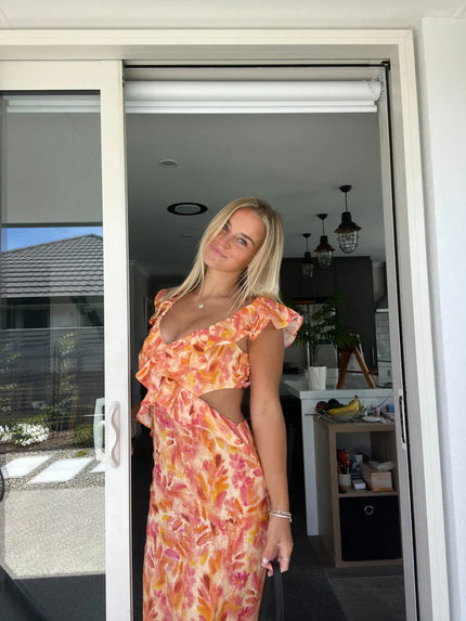 Women's orange and pink floral maxi sundress with ruffle trim and side cutouts, featuring a deep V-neckline.