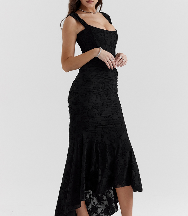 Black floral corset midi dress with ruched details and asymmetric hem, paired with black heels.