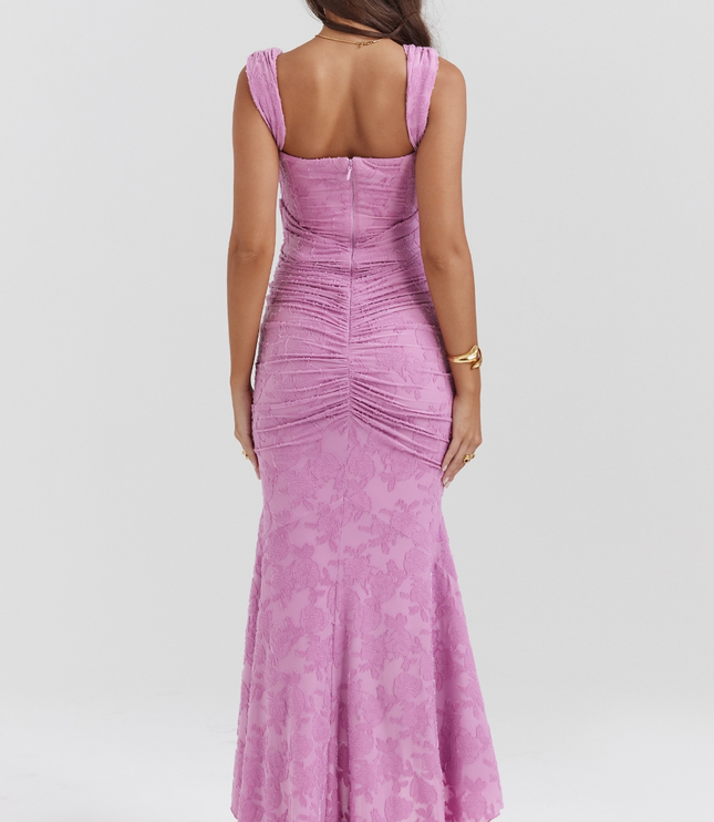 Back view of a women's pink floral corset asymmetric midi dress with ruched detailing and a subtle floral pattern, for graduation.