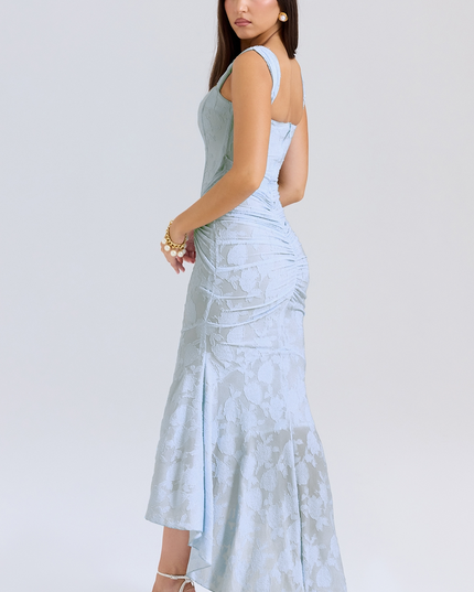 Side view of a light blue women's floral graduation dress, showcasing the fitted corset and draped asymmetric skirt with white heels.