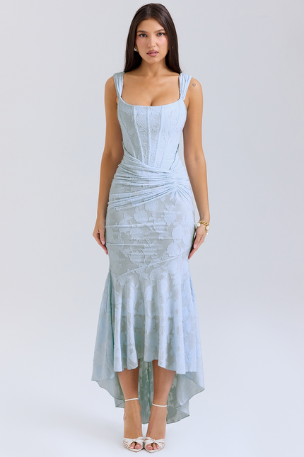 Light blue women's graduation dress with floral jacquard pattern, corset bodice, and asymmetric midi hemline, paired with white heels.