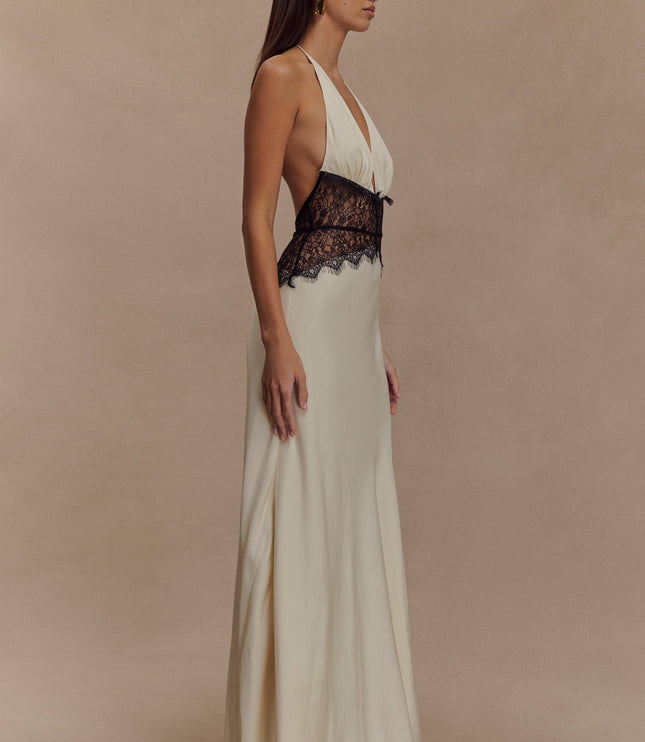 Side profile of cream halter neck maxi dress featuring a deep V-neck and black lace mid-section.