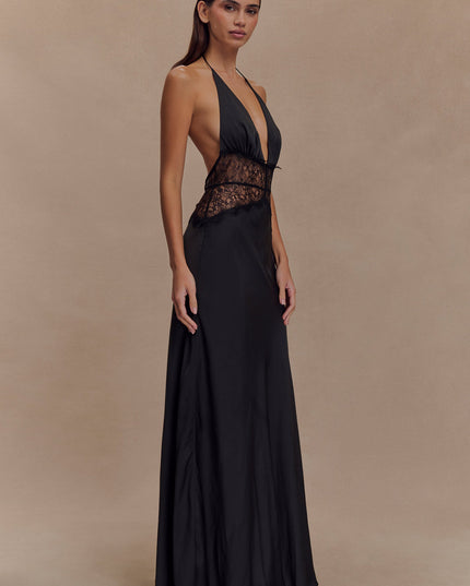 Side profile of a black halter neck maxi dress for women, highlighting the lace paneling and flowing skirt.