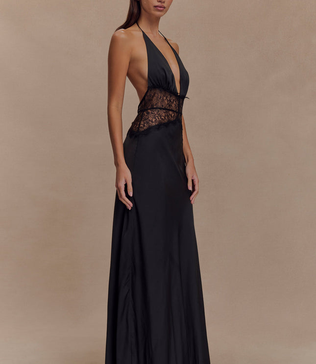 Side profile of a black halter neck maxi dress for women, highlighting the lace paneling and flowing skirt.