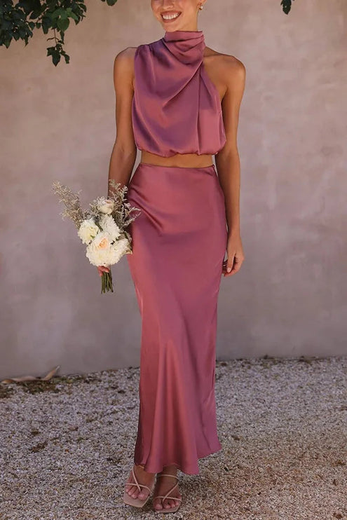Women's dusty rose pink halter neck satin crop top and long maxi skirt set, with a floral bouquet.
