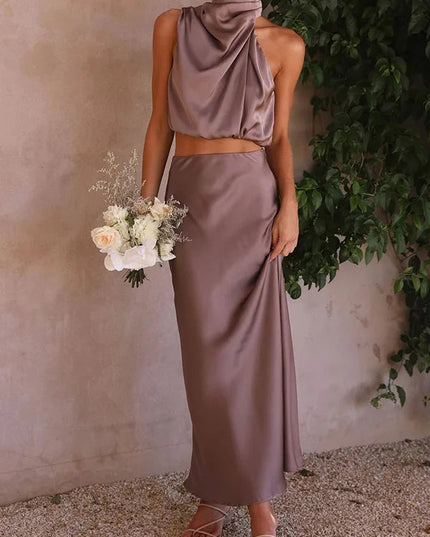 Women's taupe grey halter neck satin crop top and elegant maxi skirt set, holding a white and cream bouquet.