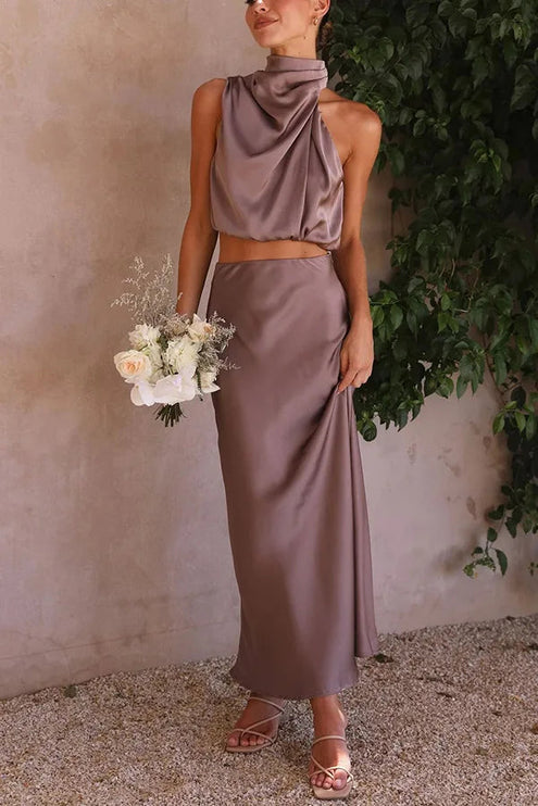 Women's taupe grey halter neck satin crop top and elegant maxi skirt set, holding a white and cream bouquet.