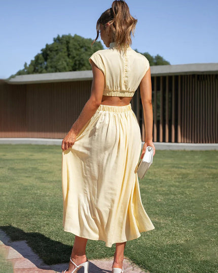 Back view of a light yellow high neck cut out pleated midi dress, with an elasticized waist.