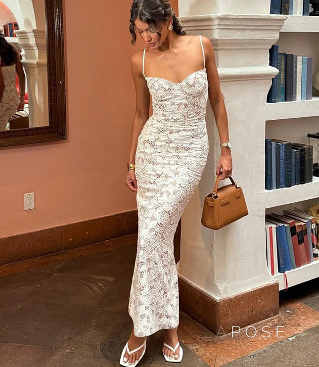White lace midi dress with ruched detailing and spaghetti straps, paired with white flat sandals and a brown handbag.