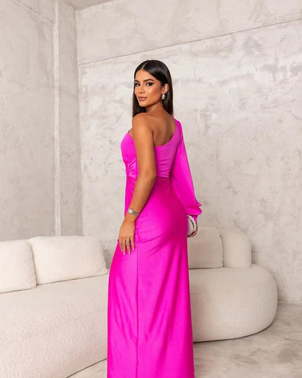 Back view of a vibrant fuchsia pink one shoulder maxi dress, highlighting the sleek fit and long sleeve of the women's dress.