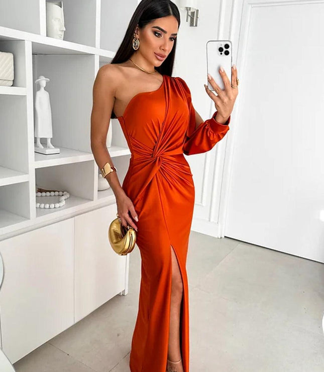 Burnt orange one-shoulder ruched maxi dress with a high slit, worn with a golden clutch and designer shoes.