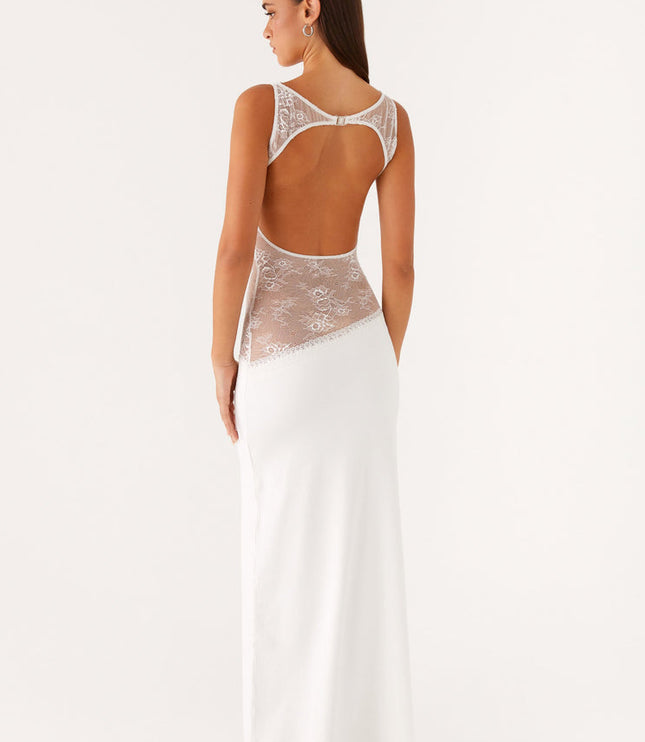 Back view of a white sleeveless maxi dress, showing an open back with a clasp closure and sheer lace panels on the sides.