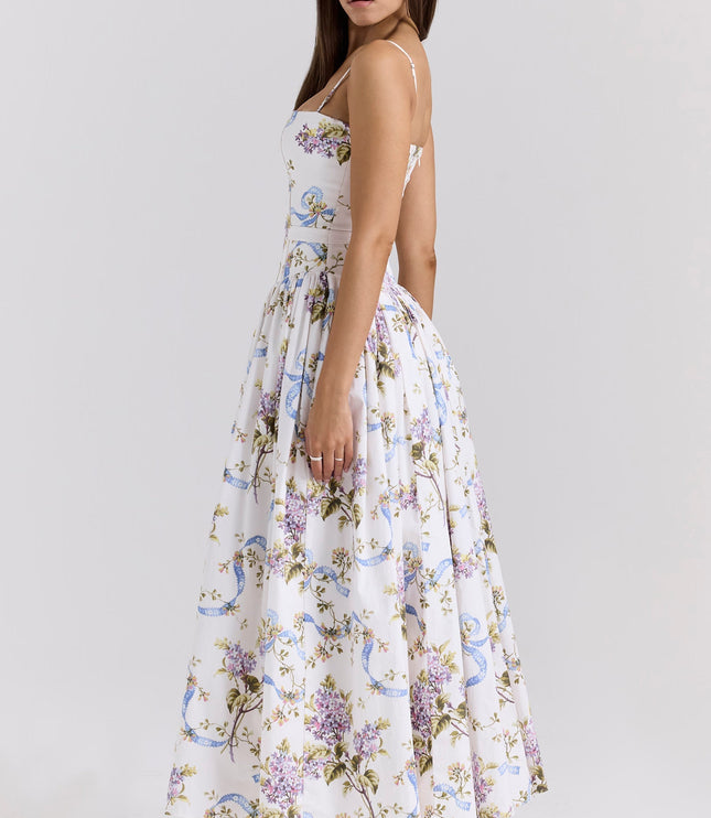 Side view of a women's white floral corset midi dress with purple and blue patterns, showcasing the full skirt and white heels.