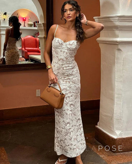 White lace spaghetti strap midi dress with a ruched effect, styled with a brown top-handle bag and gold jewelry.