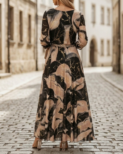 Back view of abstract print maxi dress with long sleeves, flowing skirt, and chain belt detail