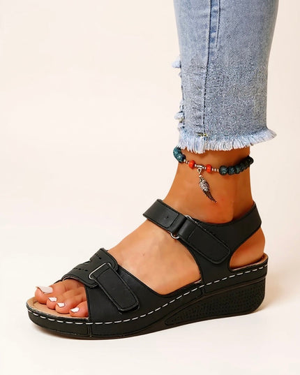 Black wedge platform sandals with wide adjustable straps and white topstitching