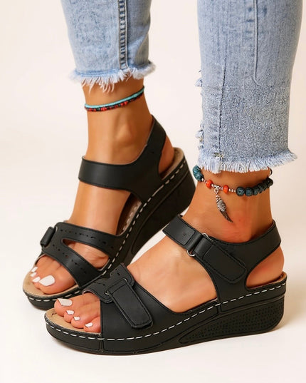 Black platform sandals with dual adjustable buckle straps worn with distressed jeans