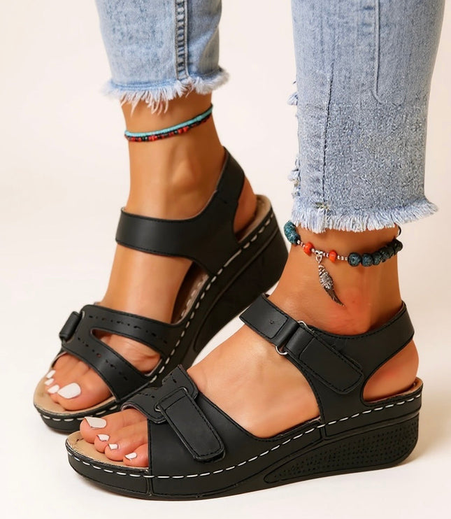 Black platform sandals with dual adjustable buckle straps worn with distressed jeans
