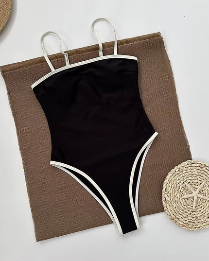 Black bandeau swimsuit styled on beach towel with straw accessories