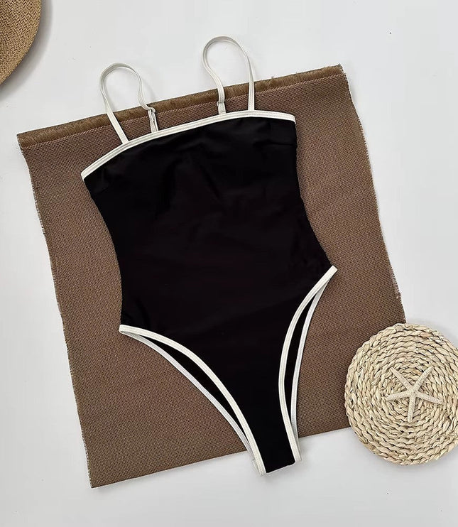 Black bandeau swimsuit styled on beach towel with straw accessories