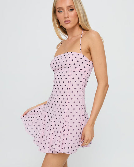 Side view of a pale pink polka dot halter mini dress with black dots, highlighting the pleated skirt.