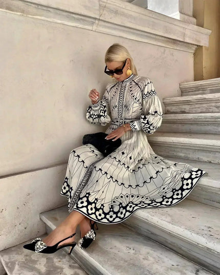 Seated view of printed midi dress showing full skirt, long sleeves, and bold floral hem
