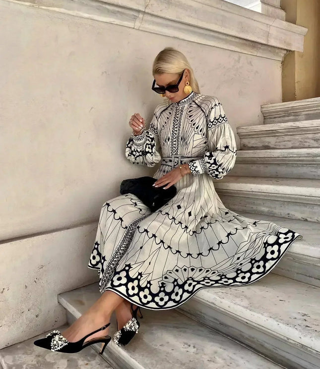 Seated view of printed midi dress showing full skirt, long sleeves, and bold floral hem