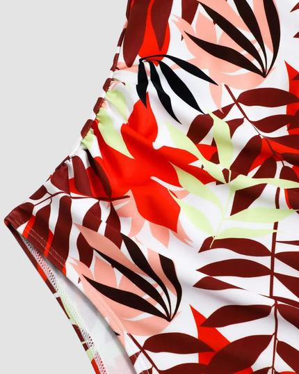 Close-up detail of red leaf print fabric and ruched side seams on swimsuit