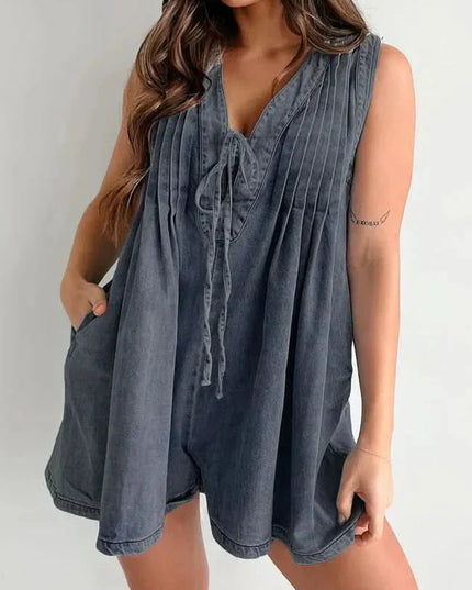 Dark washed mini denim romper for women with V-neck tie front, pleated bodice, and relaxed shorts