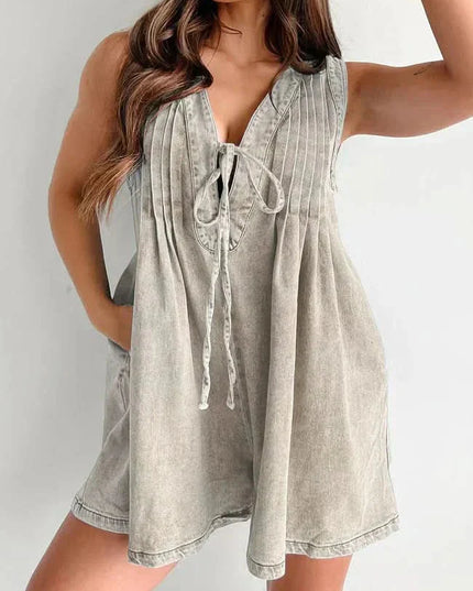 Beige washed casual mini denim romper with pleated front, tie neckline, and sleeveless summer style