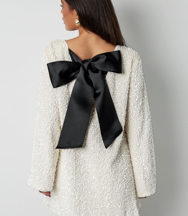 Back view of a white cocktail mini dress with a deep bow back detail and long sleeves