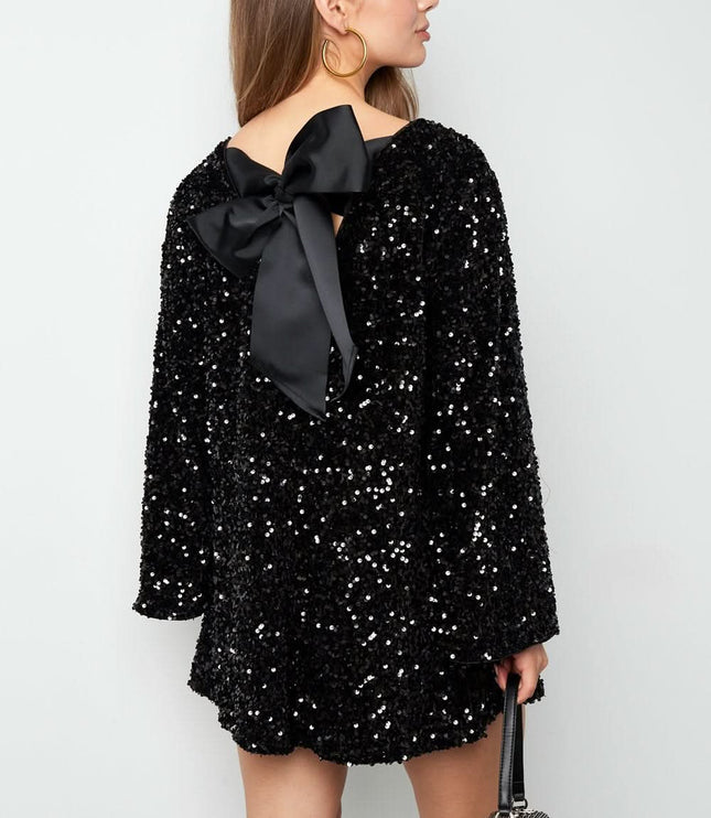 Back view of a black sequin mini dress with a large satin bow back and flared long sleeves