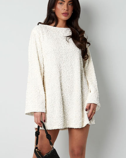 White textured mini dress with long sleeves and a loose fit, styled with a black handbag