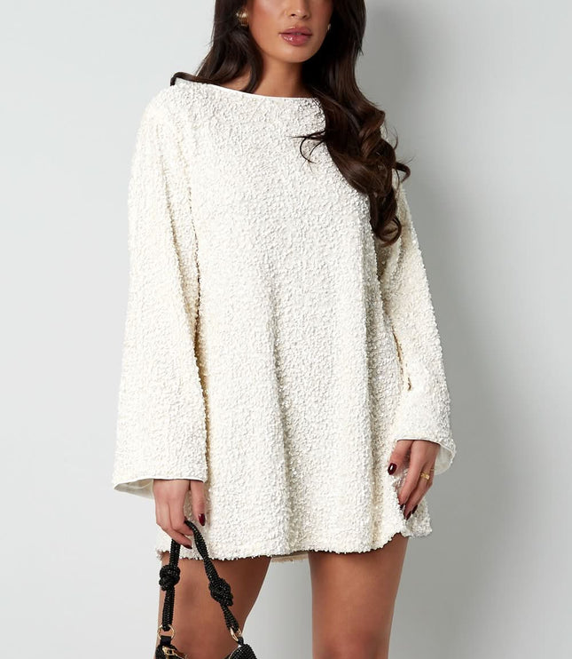 White textured mini dress with long sleeves and a loose fit, styled with a black handbag
