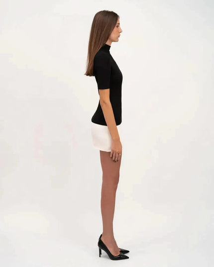 Side view of black and white color block mock neck mini dress with fitted silhouette